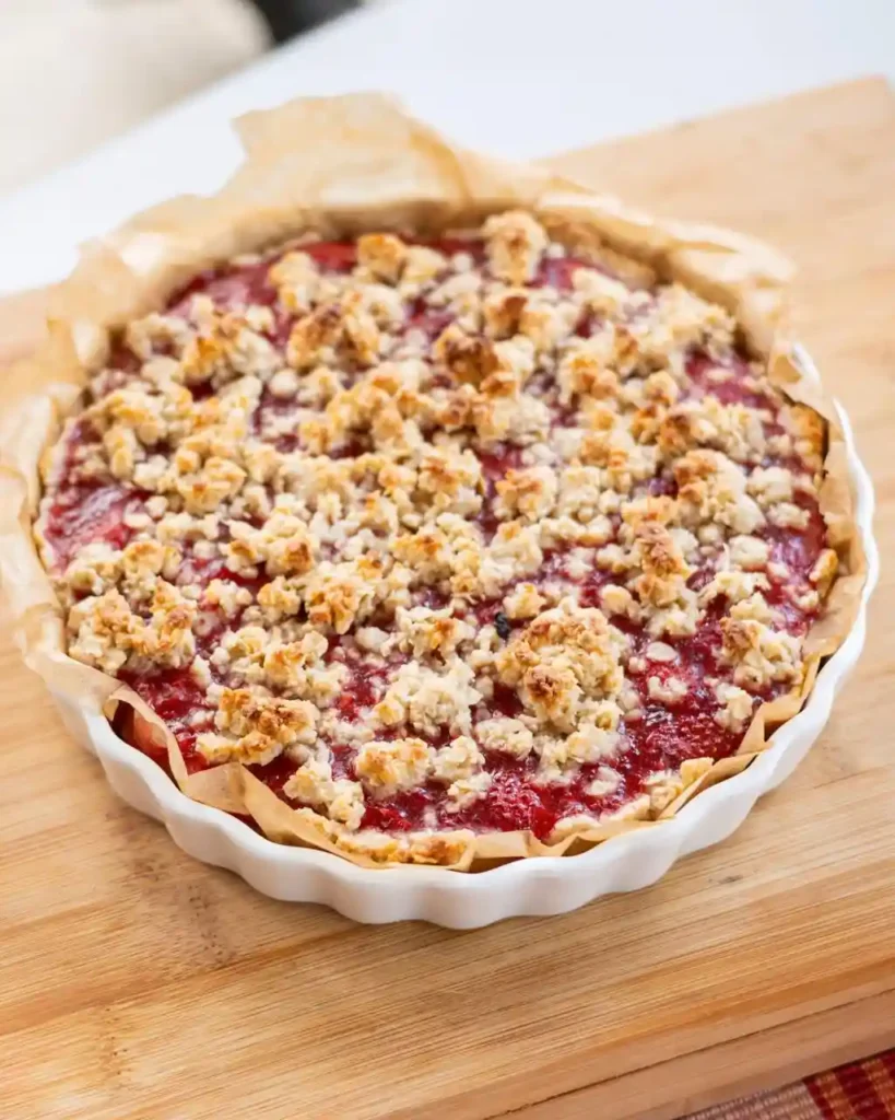 Easy Strawberry Dessert Recipes 1 A golden baked strawberry crumble in a ceramic dish with bubbling strawberry filling — one of the best baked strawberry dessert recipes